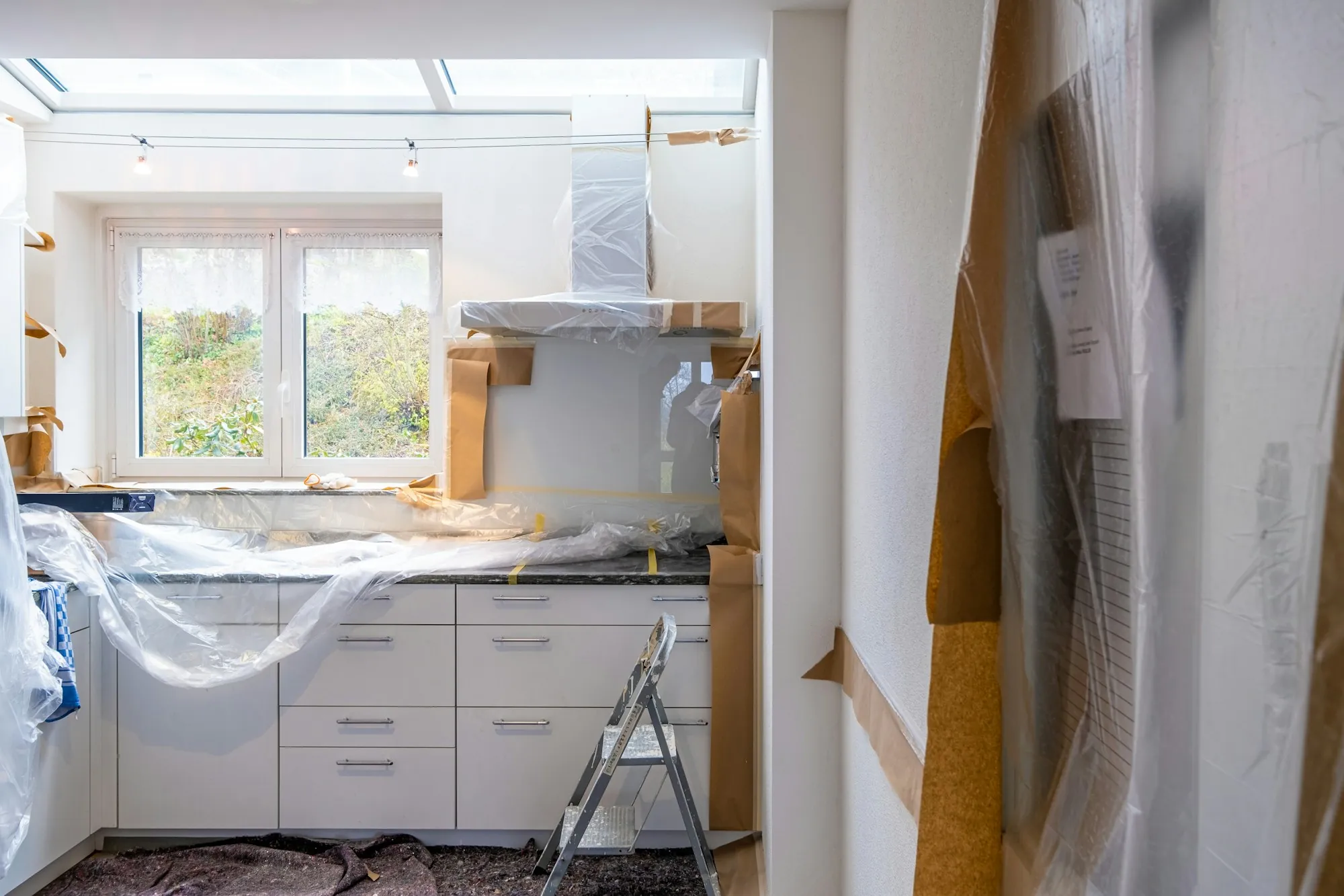 Kitchen mid-renovation with counters covered in plastic